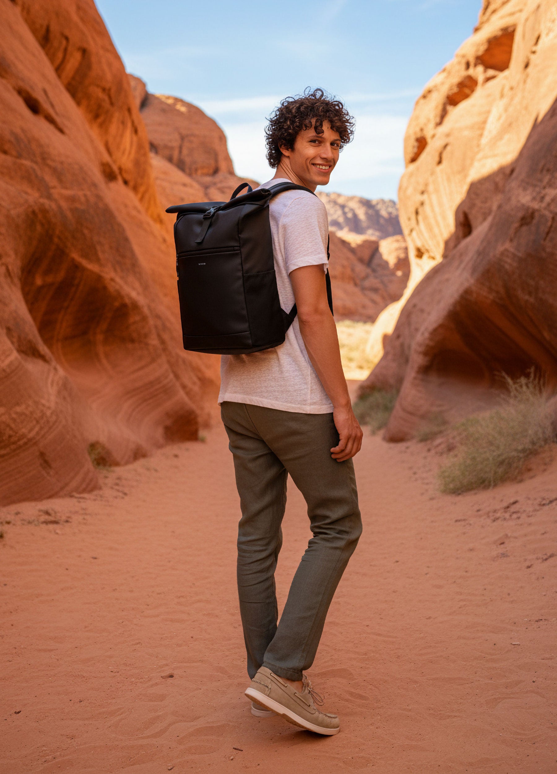 VIVID – Herr mit schwarzem Rolltop-Rucksack in weißem T-Shirt und Olive Chino im Sandstein-Canyon