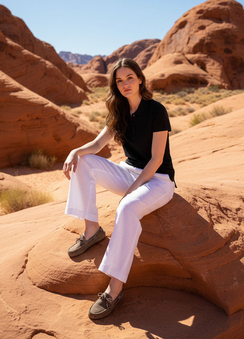 VIVID – Dame in schwarzem Polo-Shirt und weißer Wide-Leg Hose auf Sandsteinfelsen im Desert Rock Canyon