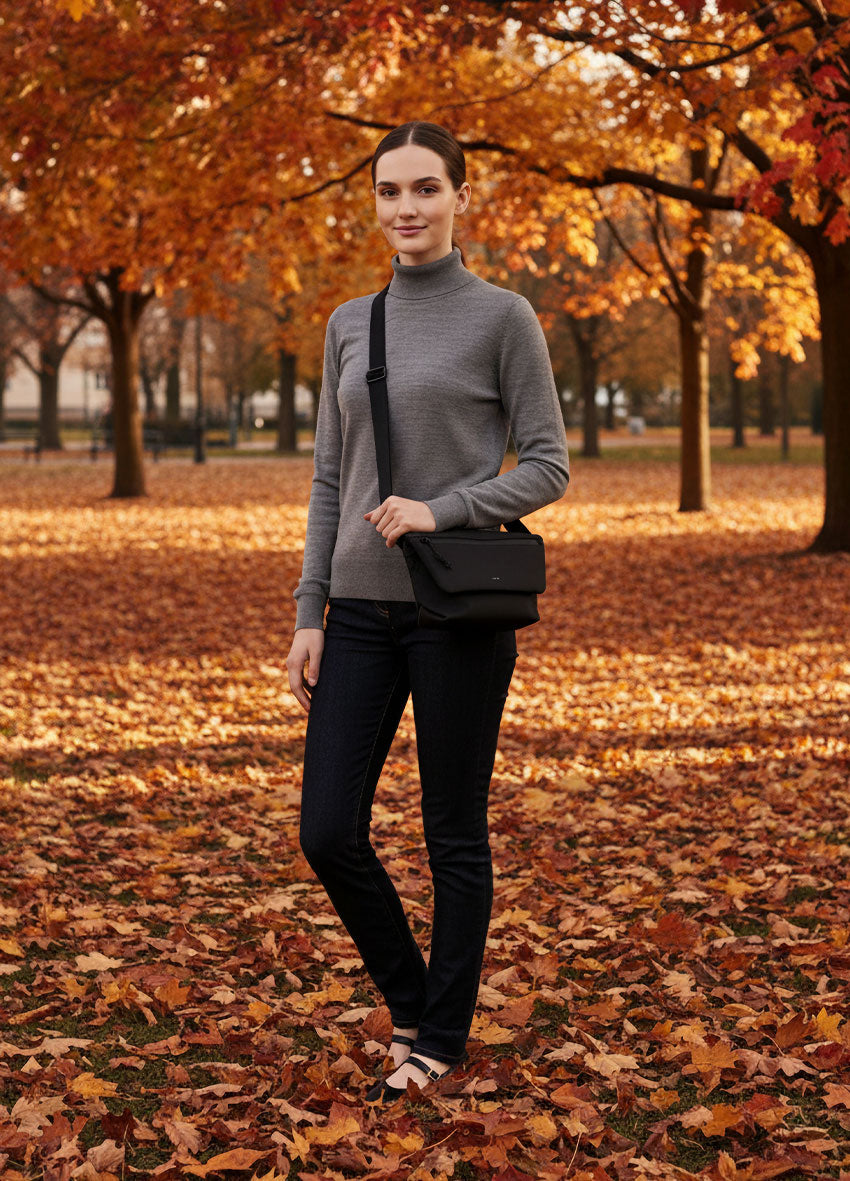 VIVID Crossbody-Bag schwarz – Damen mit grauem Rollkragen-Pullover und dunkler Jeans im herbstlichen Stadtpark