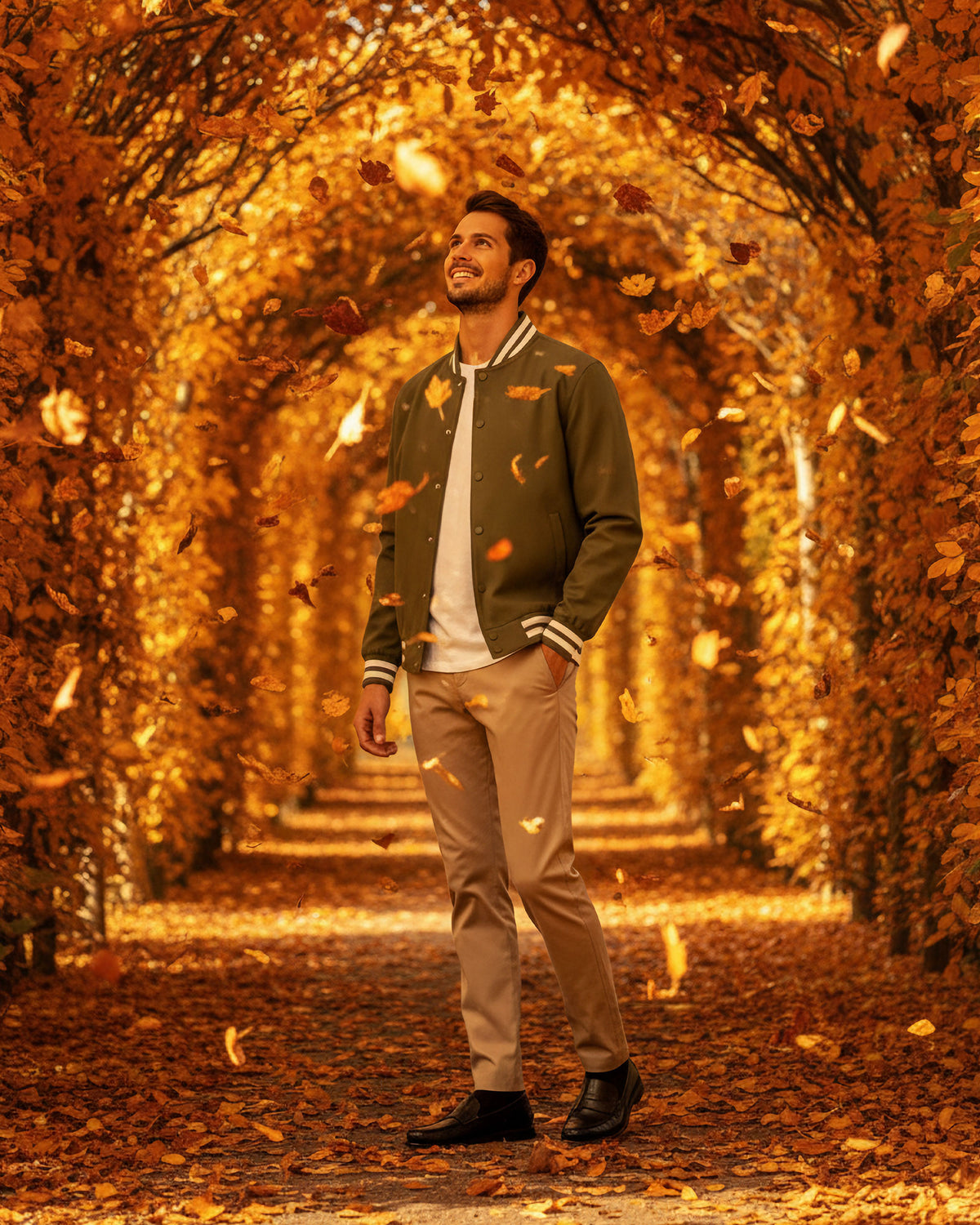 VIVID Varsity Jacke Herren oliv – Lässiges Herbst-Outfit mit beiger Chino unter goldenem Laubbogen im Stadtpark